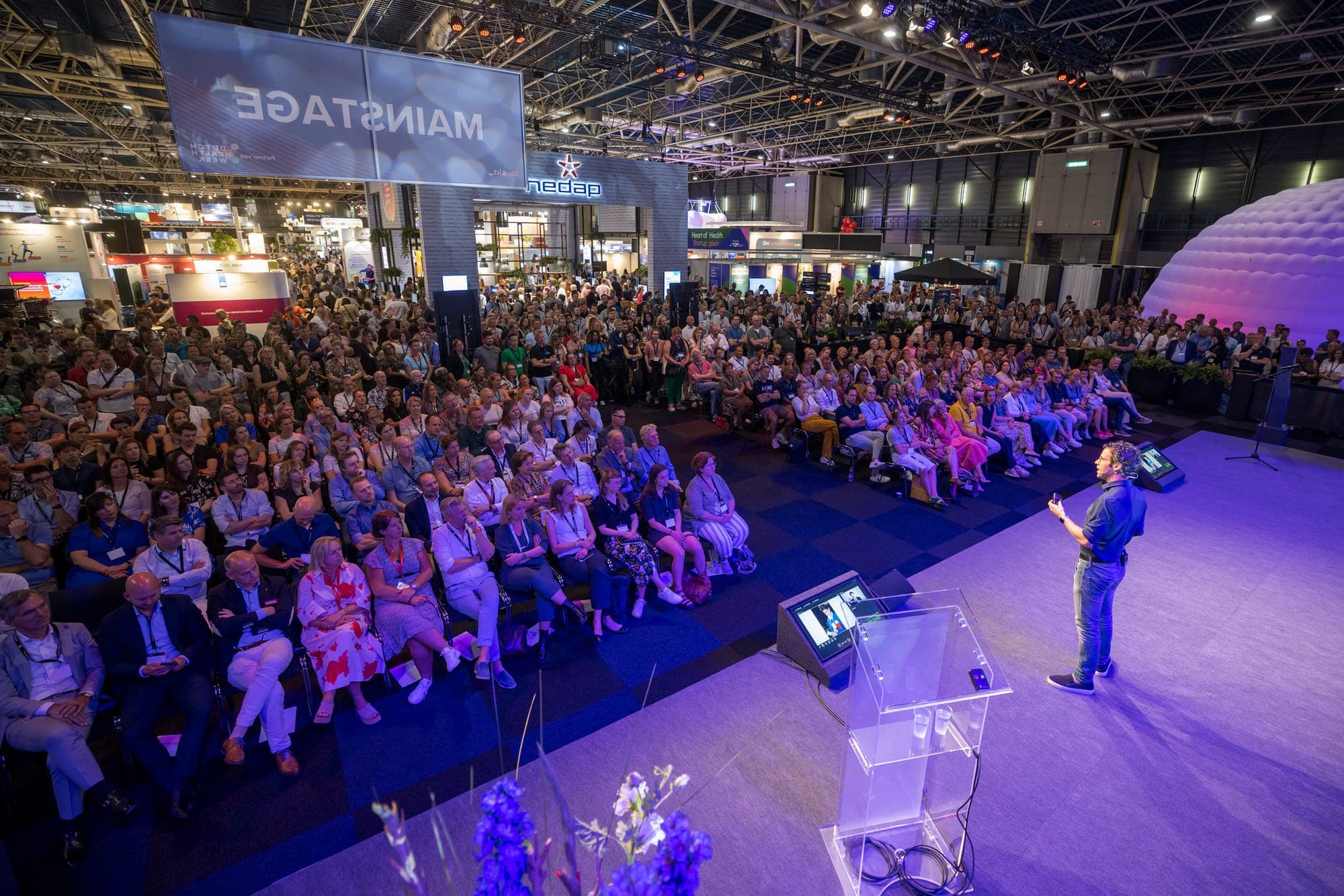 Conference photography, speaker on the main stage in front of hundreds of visitors